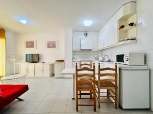 a kitchen with white cabinets and a table and chairs at Roc Mar 2 5C - Apartamento cerca del centro y de la playa - terraza con vistas al mar y al puerto in Roses