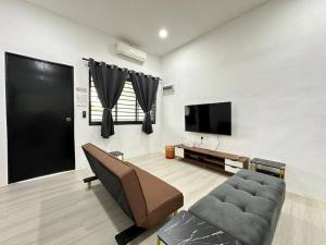 sala de estar con sofá y TV de pantalla plana en Home In Johor Bahru Near Sutera Mall, en Skudai