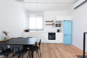 a kitchen with a table and a blue refrigerator at PORT CITY HAIFA - Luxury Seaview Penthouse w Jaccuzzi in Haifa