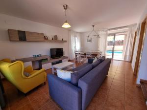 uma sala de estar com um sofá azul e cadeiras amarelas em L' Escala Casa Mallols Xrm04 em L'Escala