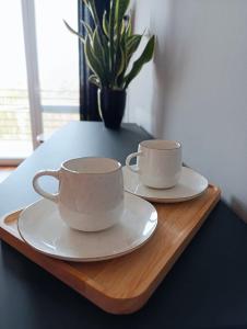 two cups and saucers sitting on a wooden tray at Willa Turkusowa in Międzyzdroje