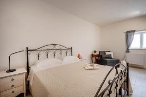 a bedroom with a large bed and a chair at Trulli Miriam: Enchanting Apulian Getaway in Martina Franca