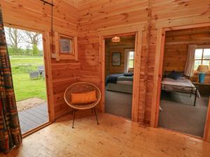 een hut met een slaapkamer, een bed en een stoel bij Manor Farm Cabin 