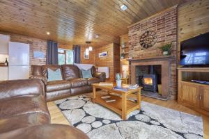 ein Wohnzimmer mit einem Ledersofa und einem Kamin in der Unterkunft Dunnock Lodge with Hot-tub in Carlisle