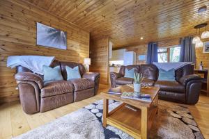 ein Wohnzimmer mit 2 Ledersofas und einem Tisch in der Unterkunft Dunnock Lodge with Hot-tub in Carlisle