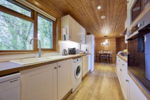 a kitchen with a sink and a washing machine at Dunnock Lodge with Hot-tub in Carlisle