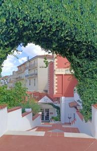Blick auf ein Gebäude durch einen Bogen von Bäumen in der Unterkunft Albergo Mango in Francavilla in Sinni