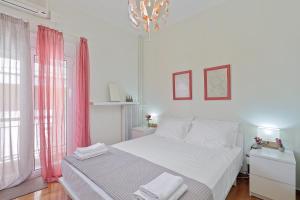 Habitación blanca con cama y lámpara de araña. en Faliron Urban Retreat, en Atenas