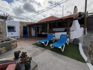 une terrasse avec 2 chaises bleues et une maison dans l'établissement La cuadra de Juan, à Icod de los Vinos