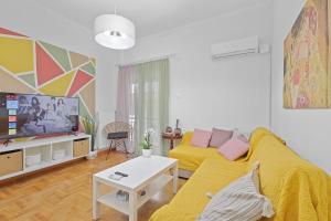 sala de estar con sofá amarillo y TV en Faliron Urban Retreat, en Atenas