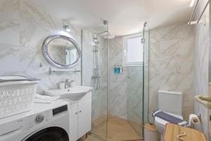 baño blanco con ducha y lavamanos en Faliron Urban Retreat, en Atenas
