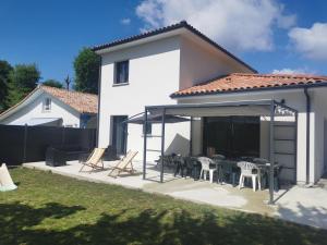 a white house with a patio with tables and chairs at Maison familiale Andernos in Andernos-les-Bains