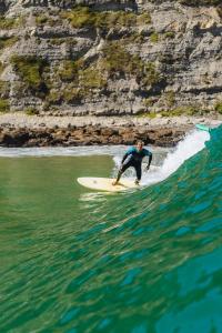 Un uomo che cavalca un'onda su una tavola da surf nell'oceano di Liquid Surfhouse a Langre