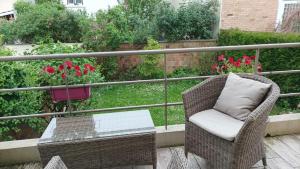 a wicker chair and table on a balcony with flowers at Comme à la maison près de Paris in Cachan