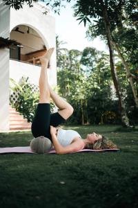 una mujer haciendo una pose de yoga en la hierba en Black Honey, en Ahangama