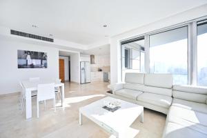 een woonkamer met een witte bank en een tafel bij Park Tzameret 3BR Panoramic by HolyGuest in Tel Aviv