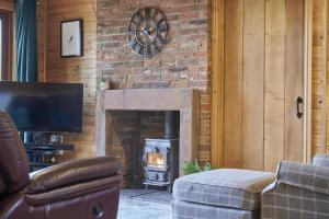 a living room with a fireplace with a stove at Fieldfare Lodge with Hot-tub in Carlisle