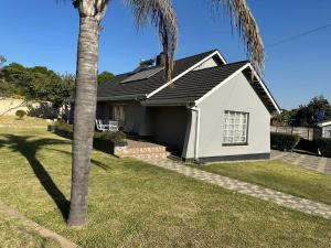 Impeccable 3-Bed House in Harare في هراري: منزل أبيض مع نخلة في الفناء