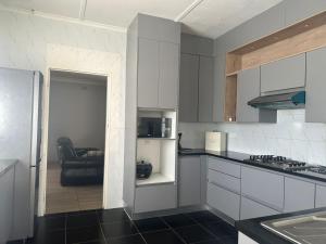 een keuken met witte kasten en een zwarte vloer bij Impeccable 3-Bed House in Harare in Harare