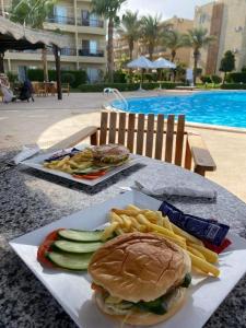 a sandwich and french fries on a table near a pool at Chez Sam in Sharm El Sheikh