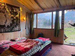 a bedroom with a bed and a large window at Zevibes Cafe & Homestay in Kalgha