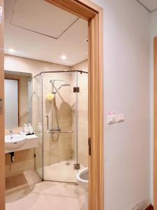 a bathroom with a shower and a toilet and a sink at Mon Cherry Apartment -Greenbay Garden Ha Long in Ha Long