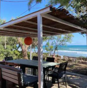 a table and chairs under a pergola with the beach at Summer front sea house for a relaxing get-away! in Pýrgos