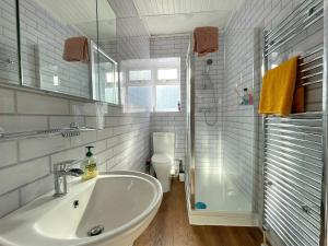 uma casa de banho com um lavatório, um chuveiro e um WC. em Sheffield's 3BR Retreat em Hillsborough
