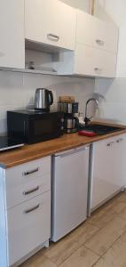 a kitchen with white cabinets and a black microwave at Apartament 2 przy Termach Cieplickich in Jelenia Góra