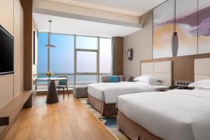 een hotelkamer met 2 bedden en een televisie bij Crowne Plaza Beihai Silver Beach, an IHG Hotel in Beihai