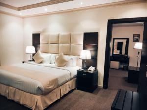 فندق ميلانا Milana Hotel في جدة: غرفة نوم بسرير كبير فيها مصباحين ومرآة