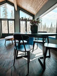 a dining room with a table and chairs and windows at Cozy Mountain Cottage with beautiful views & Sauna in Beitostøl