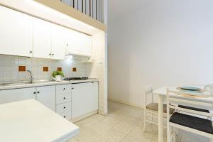 cocina con armarios blancos, mesa y sillas en Appartamento Turchese PT - MyHo Casa, en Alba Adriatica