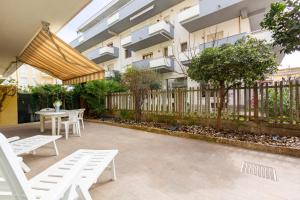 un patio con mesas y sillas blancas y un edificio en Appartamento Turchese PT - MyHo Casa, en Alba Adriatica