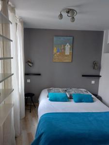 a bedroom with a large bed with blue pillows at Home St. Germain in Trouville-sur-Mer