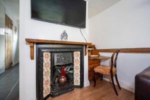 a living room with a fireplace with a tv on the wall at Wits End Cottage in Mildenhall