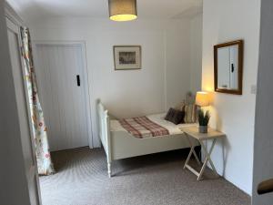 ein kleines Schlafzimmer mit einem Bett und einem Tisch in der Unterkunft White Cottage Newport, Pembrokeshire in Newport