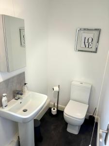 La salle de bains est pourvue de toilettes blanches et d'un lavabo. dans l'établissement THE GARDEN SUITE, à Denby