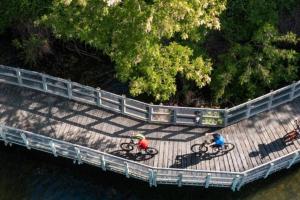 two people riding bikes on a bridge over the water at Gardeners' Cottage in Hamilton