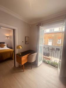 Amazing Newly Refurbished Mews House in W1 في لندن: غرفة نوم مع مكتب وسرير ونافذة
