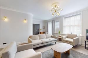 ein Wohnzimmer mit weißen Möbeln und einem Kronleuchter in der Unterkunft Amazing Newly Refurbished Mews House in W1 in London