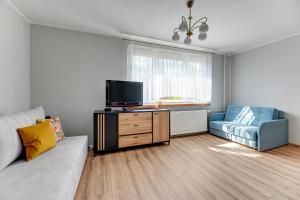 sala de estar con sofá, TV y silla en Wejhera by Comfort Apartments, en Jelitkowo