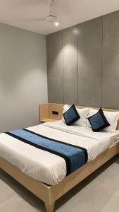 a bedroom with a large bed with blue pillows at Hotel Golden Suites - Near Nesco in Mumbai