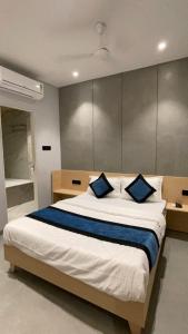 a bedroom with a large bed with two blue pillows at Hotel Golden Suites - Near Nesco in Mumbai