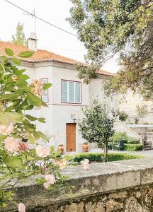 een wit huis met een bruine deur en roze bloemen bij Quinta Costa da Estrela in Gouveia