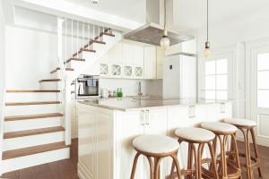 a kitchen with white cabinets and bar stools at Tuyo Apartments Blue City in Warsaw