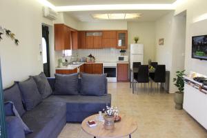 a living room with a blue couch and a kitchen at Villa Alimedon in Almirida