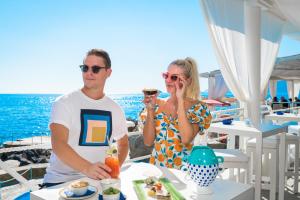 a man and a woman sitting at a table with a drink at Grand Hotel Tritone in Praiano