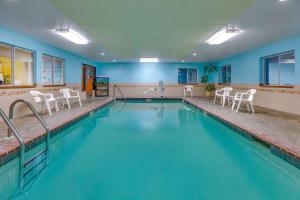 a large swimming pool with white chairs in a room at Super 8 by Wyndham Roswell in Roswell