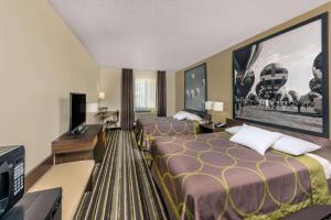 a hotel room with two beds and a flat screen tv at Super 8 by Wyndham Roswell in Roswell